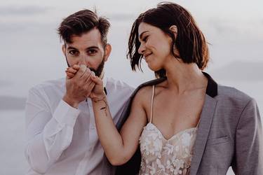 Le marié dépose un baiser sur la main de sa mariée souriante