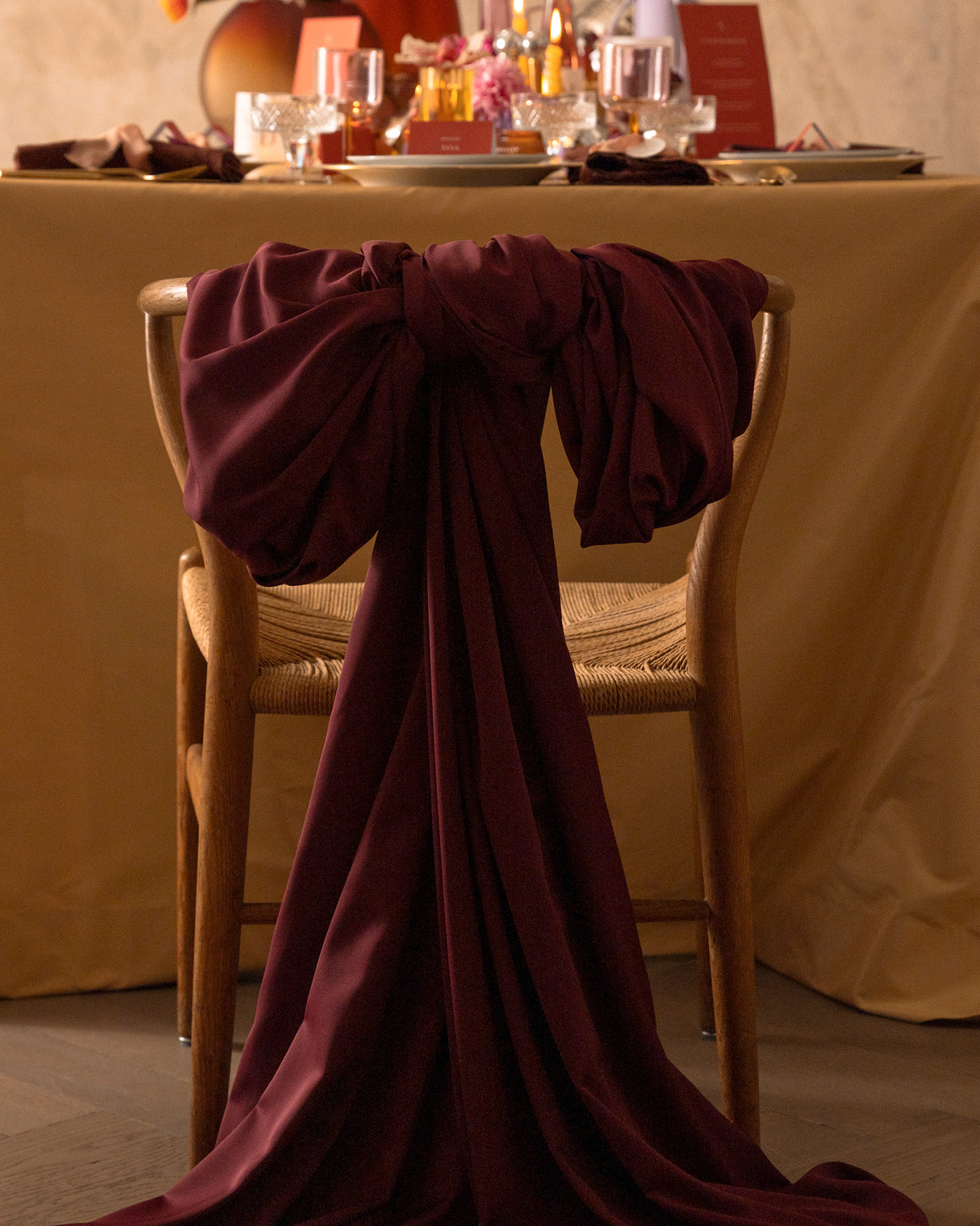 Chaise décorée d’un grand nœud en tissu, placée devant une table de mariage.