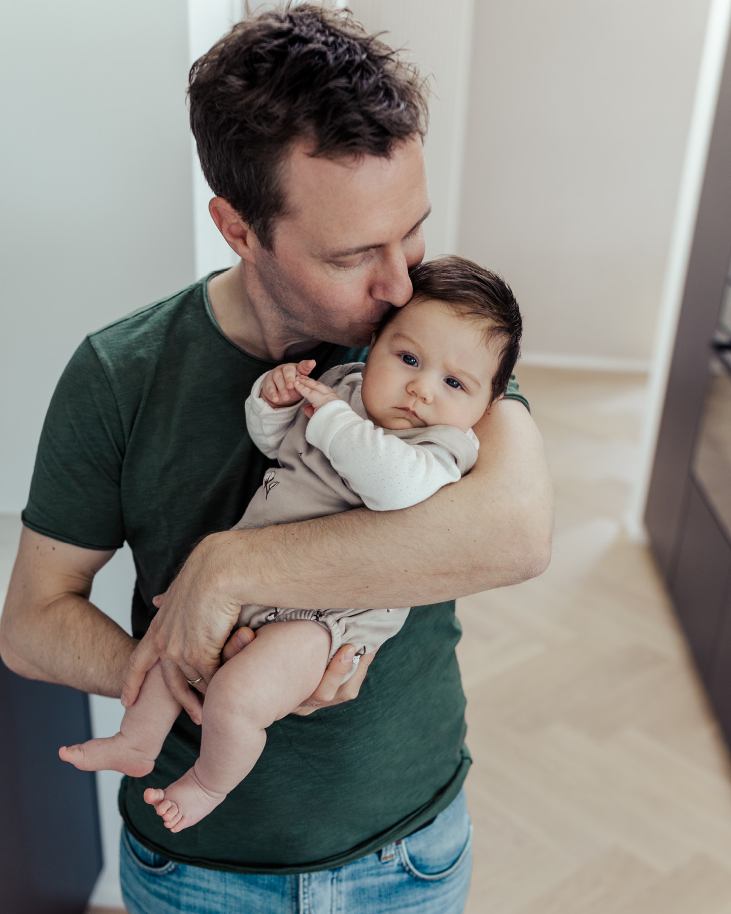 Un papa embrasse tendrement son bébé dans ses bras.