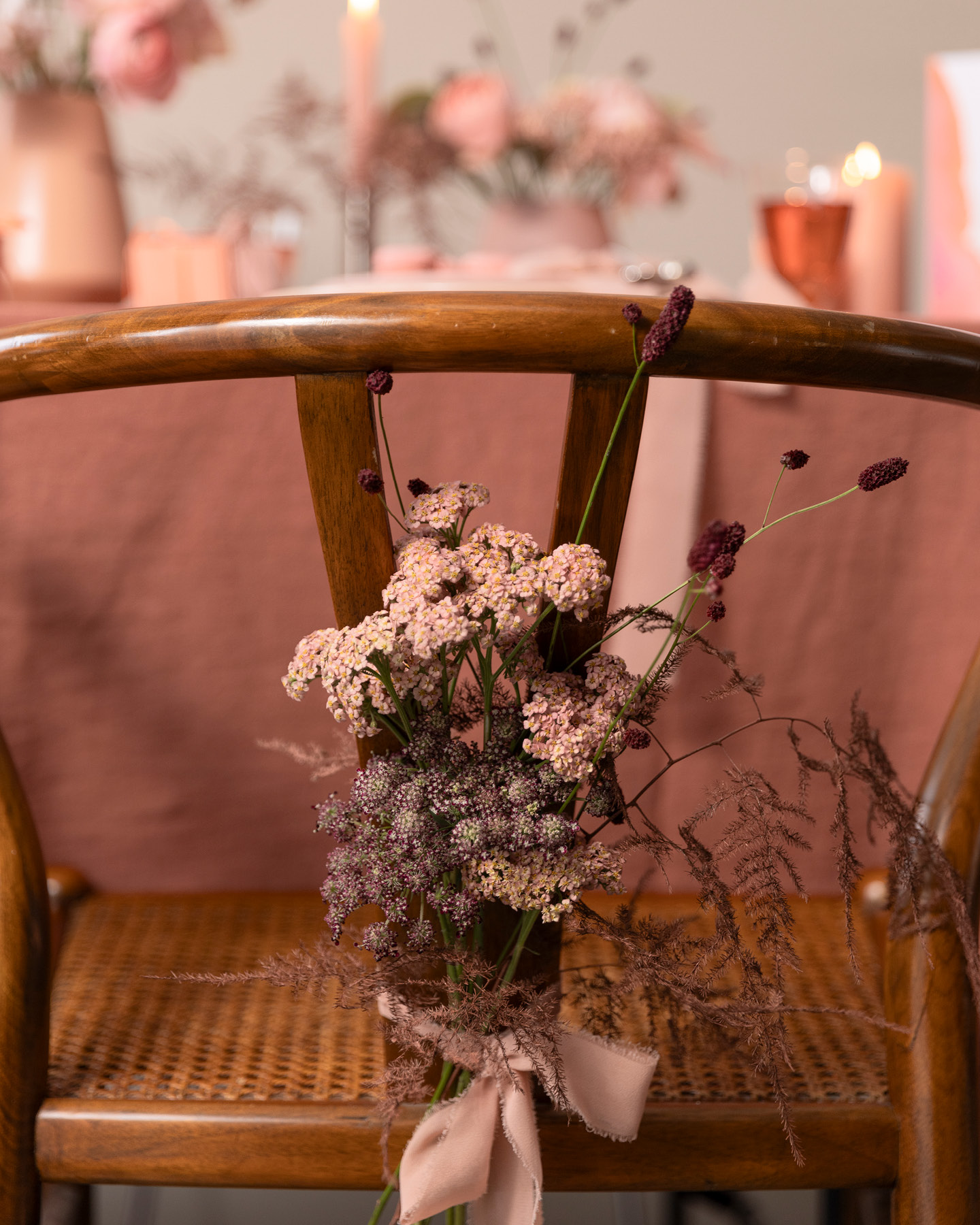 Dossier de chaise décoré d’un nœud en tissu et d’un arrangement fleuri.