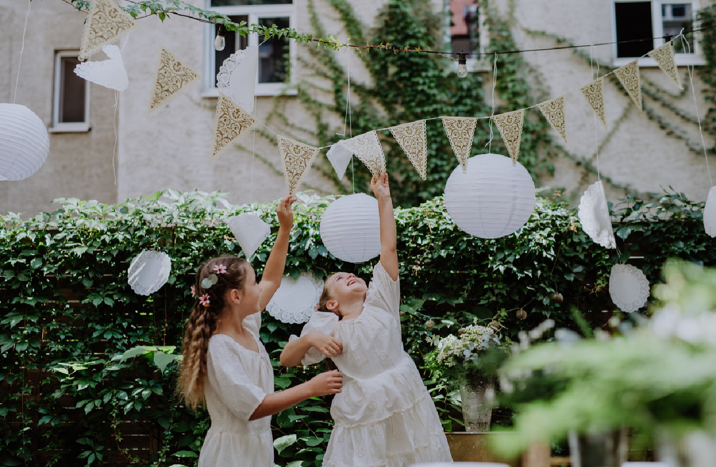 De petites filles jouent avec une guirlande dans le jardin lors d’un mariage.