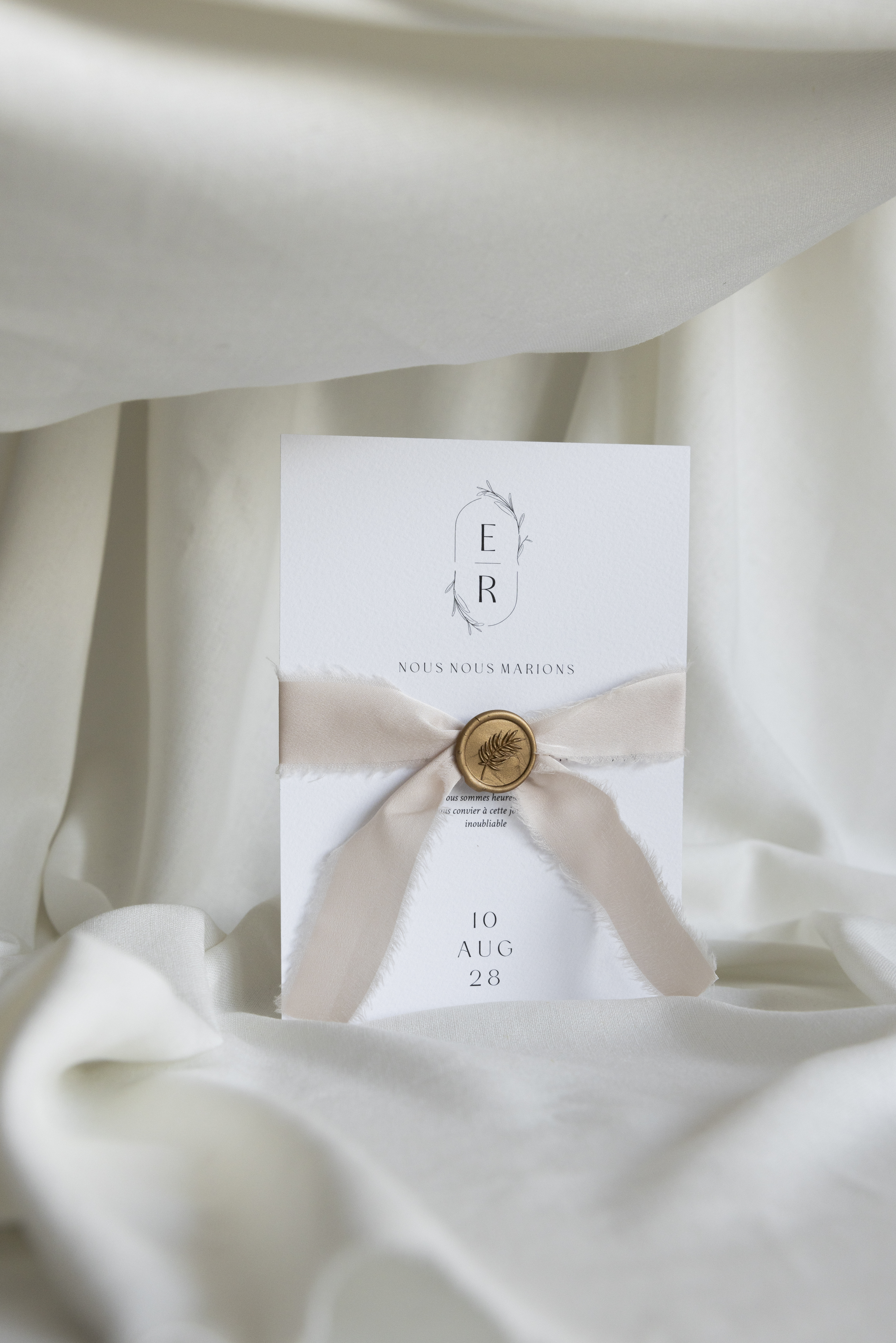 Faire-part de mariage noué d’un ruban, délicatement posé sur une assiette.