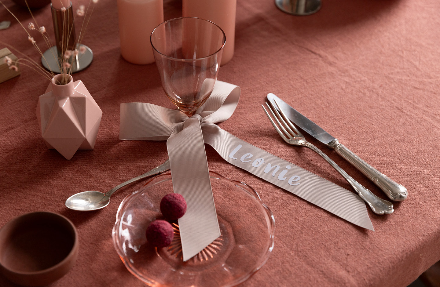 Verre à vin orné d’un ruban personnalisé au nom de l’invité, disposé sur une table de mariage.