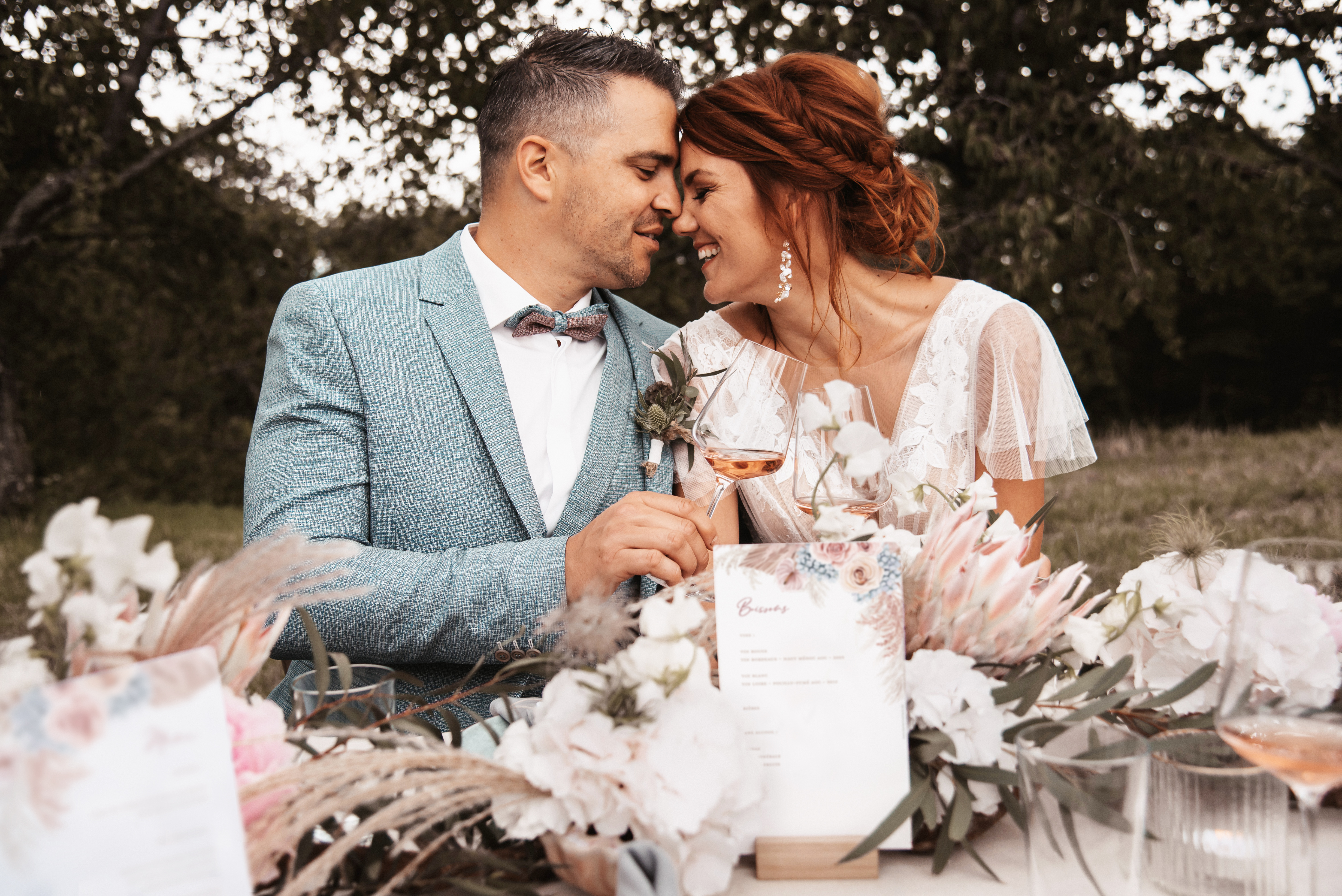 Des mariés boho heureux trinquent à leur mariage.