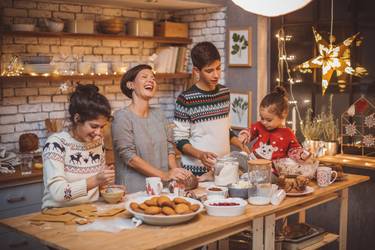 Mother with children in kitchen preparing Christmas cakes