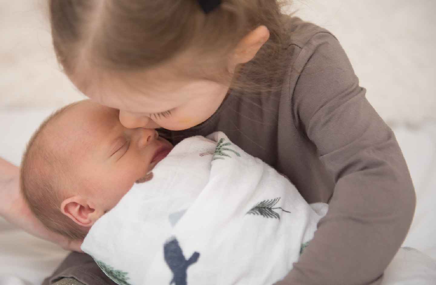 Une petite fille embrasse tendrement son petit frère endormi.