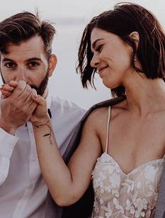Le marié dépose un baiser sur la main de sa mariée souriante