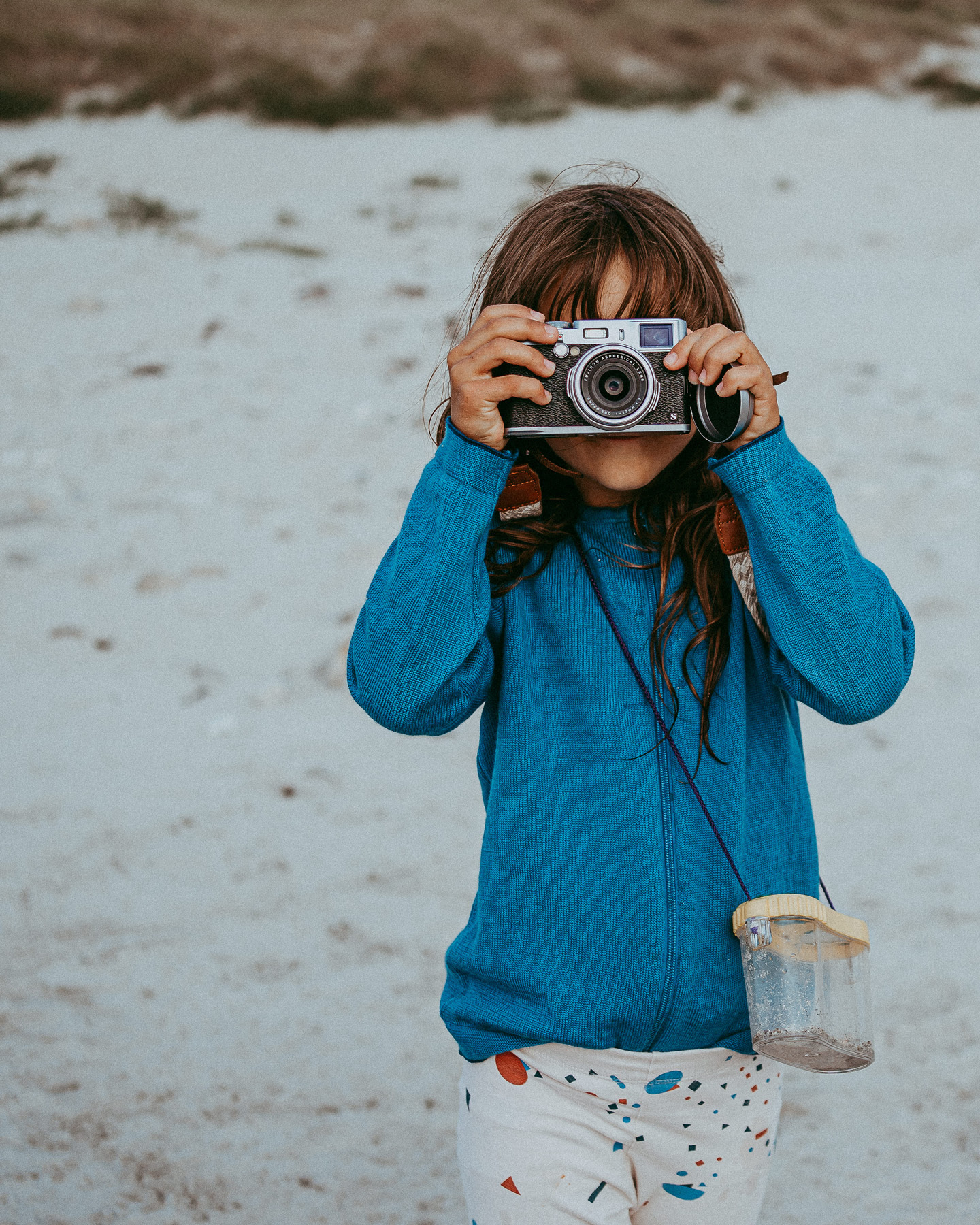 Une fillette sur la plage, l’appareil photo devant le visage.