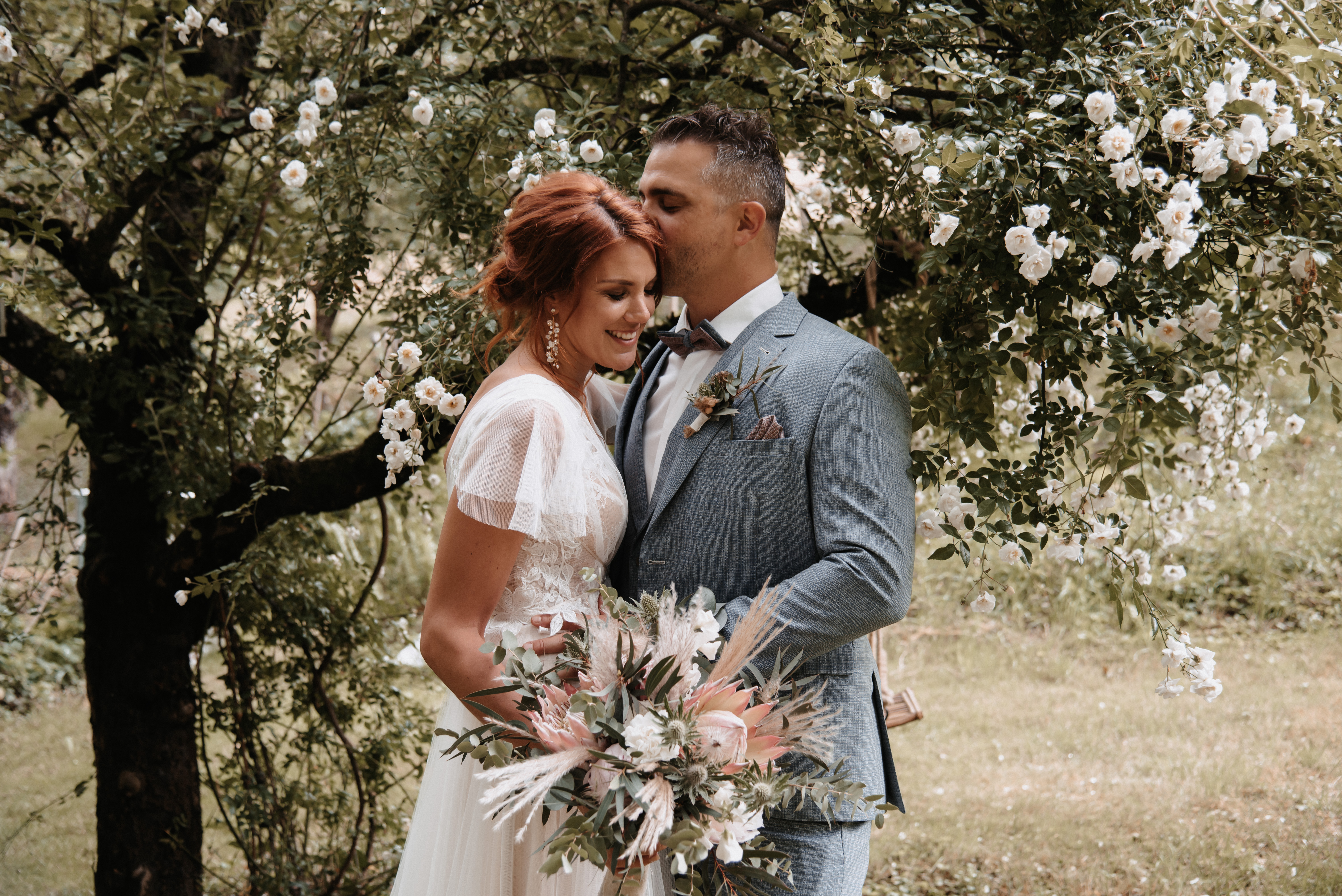 Des jeunes mariés amoureux avec un bouquet de mariée boho élaboré