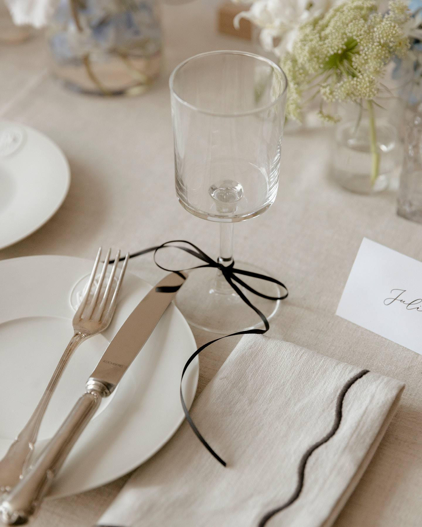 Verre à vin orné d’un ruban, délicatement disposé sur une table de mariage.
